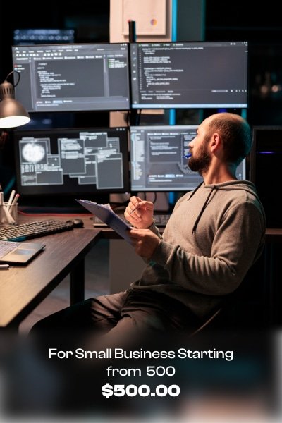 a man sitting at a desk with multiple computer screens